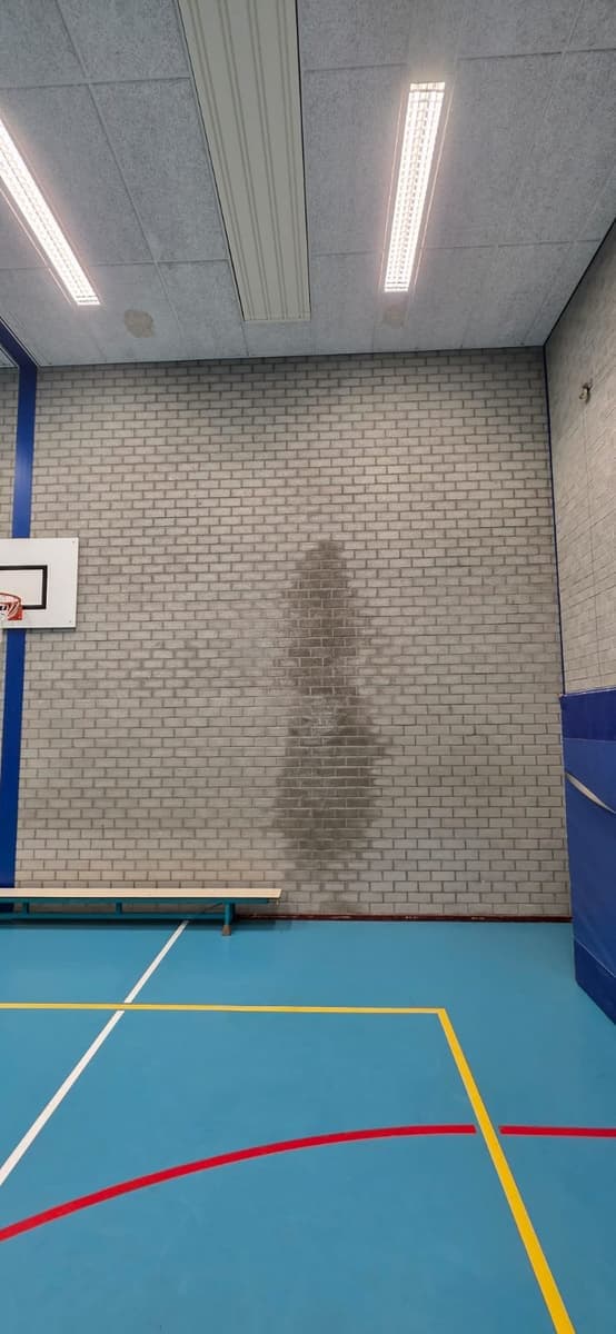 Gymzaal met grote vochtplek op de muur